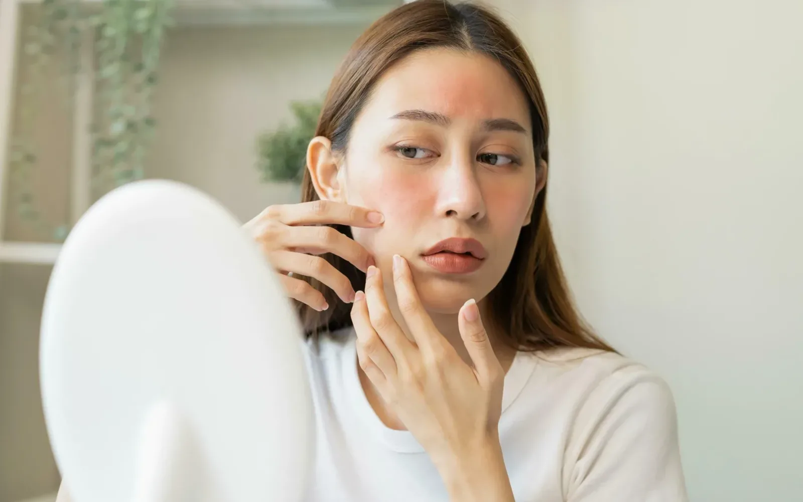 Người phụ nữ nhìn vào gương, hai má và trán đỏ rát